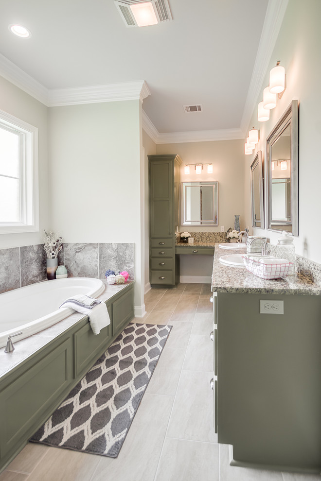 This is an example of a large traditional master bathroom in New Orleans with flat-panel cabinets, green cabinets, a drop-in tub, an alcove shower, a two-piece toilet, beige tile, ceramic tile, beige walls, cement tiles, a drop-in sink, granite benchtops, beige floor, an open shower and beige benchtops.