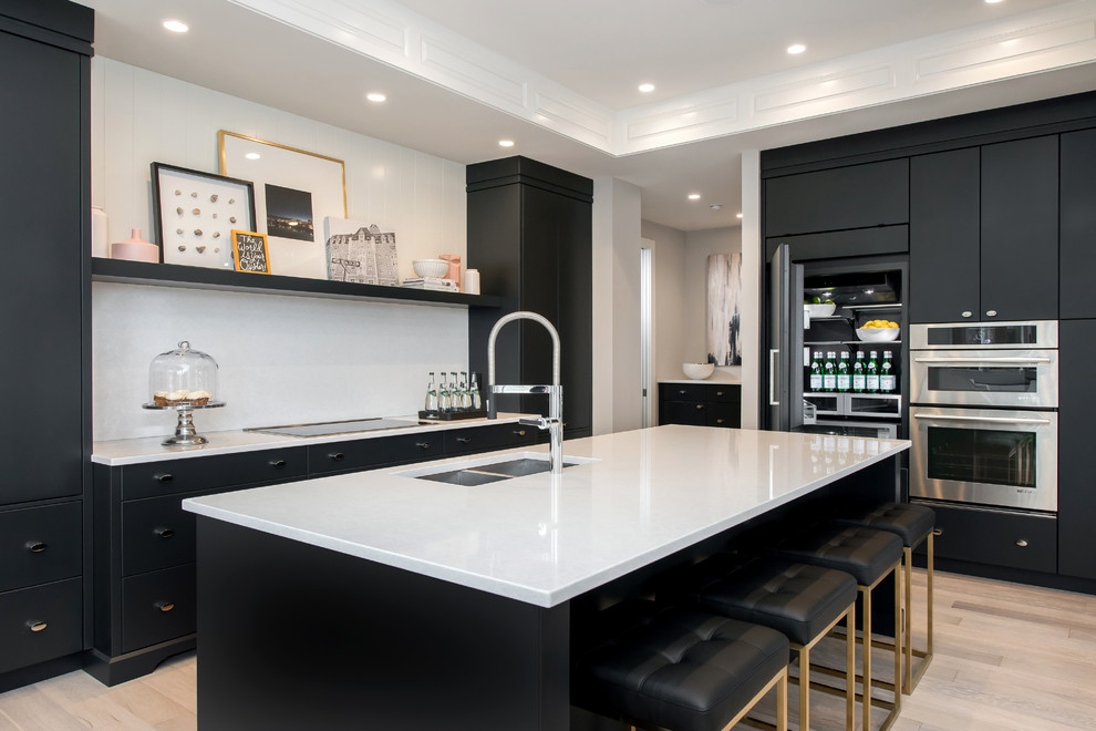 Inspiration for a large transitional l-shaped light wood floor eat-in kitchen remodel in Calgary with an undermount sink, flat-panel cabinets, gray cabinets, quartz countertops, white backsplash, stone tile backsplash, paneled appliances and an island