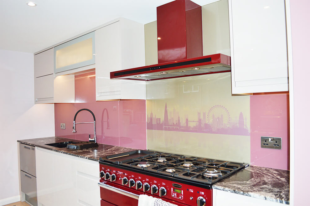 Photo of a large modern eat-in kitchen in Hertfordshire with flat-panel cabinets, white cabinets, marble benchtops, pink splashback, glass sheet splashback and with island.