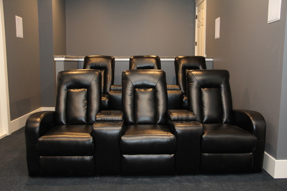 This is an example of a large arts and crafts enclosed home theatre in Charlotte with carpet, a built-in media wall and grey walls.