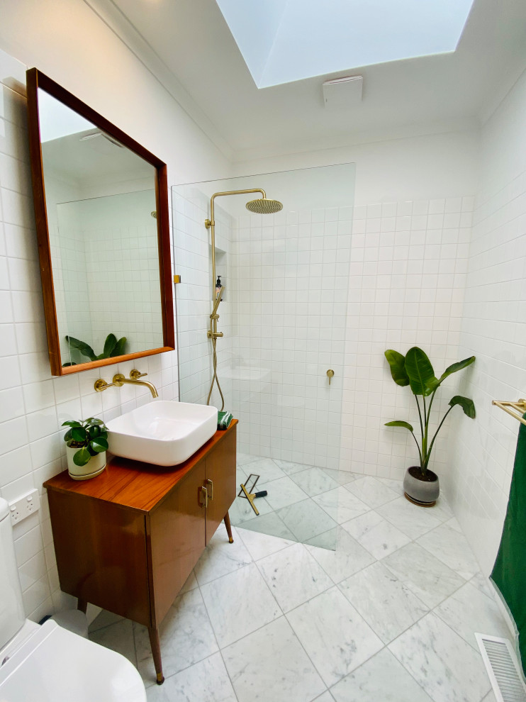 Modern inredning av ett mellanstort brun brunt en-suite badrum, med skåp i mellenmörkt trä, en öppen dusch, en toalettstol med hel cisternkåpa, vit kakel, keramikplattor, marmorgolv, ett fristående handfat, träbänkskiva, grått golv och med dusch som är öppen