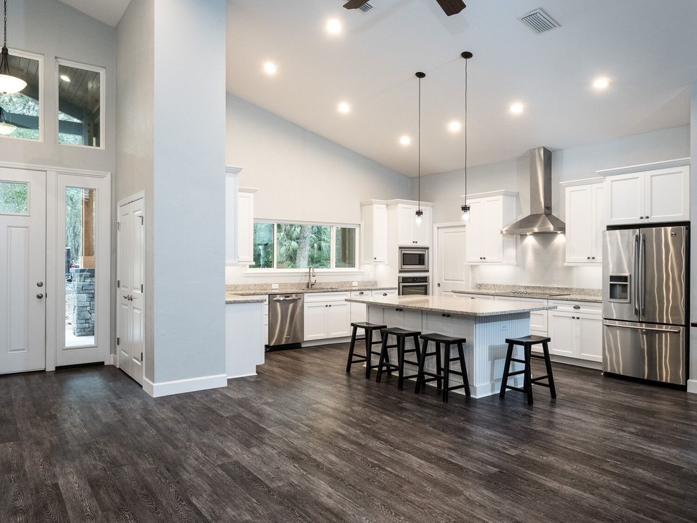 Inspiration for a mid-sized transitional l-shaped open plan kitchen in Miami with an undermount sink, recessed-panel cabinets, white cabinets, granite benchtops, stainless steel appliances, dark hardwood floors, with island, brown floor and grey benchtop.