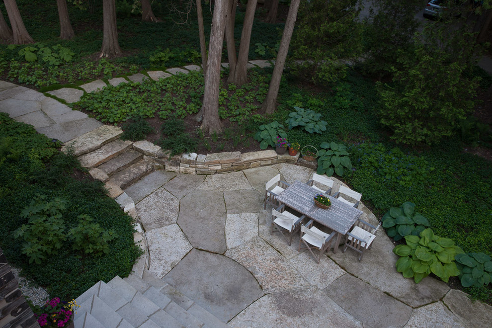Photo of a large country side yard patio in Other with natural stone pavers.