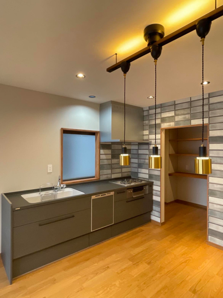 Inspiration for a medium sized urban grey and black single-wall open plan kitchen in Nagoya with a submerged sink, flat-panel cabinets, distressed cabinets, metro tiled splashback, stainless steel appliances, medium hardwood flooring, brown floors, black worktops and a wallpapered ceiling.
