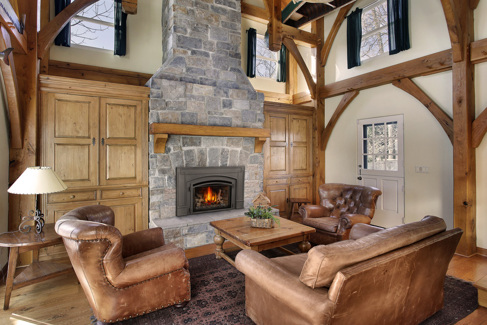 Photo of a large country formal open concept living room in Other with beige walls, medium hardwood floors, a standard fireplace, a stone fireplace surround, no tv and brown floor.