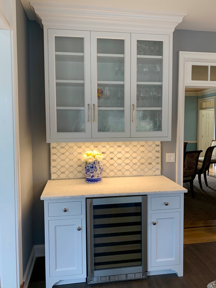 Photo of a small traditional single-wall home bar in Other with glass-front cabinets, white cabinets, quartzite benchtops, blue splashback, marble splashback, cork floors, brown floor and grey benchtop.