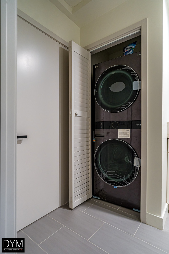 This is an example of a mid-sized contemporary laundry cupboard in Orange County with white splashback, ceramic splashback, white walls, ceramic floors, a concealed washer and dryer, grey floor, wallpaper and wallpaper.