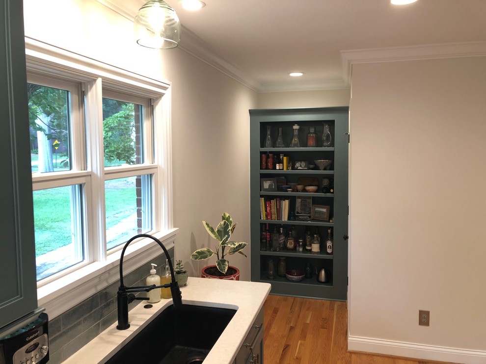 Design ideas for an expansive eclectic galley separate kitchen in Raleigh with a single-bowl sink, flat-panel cabinets, green cabinets, quartzite benchtops, green splashback, cement tile splashback, black appliances, light hardwood floors and white benchtop.