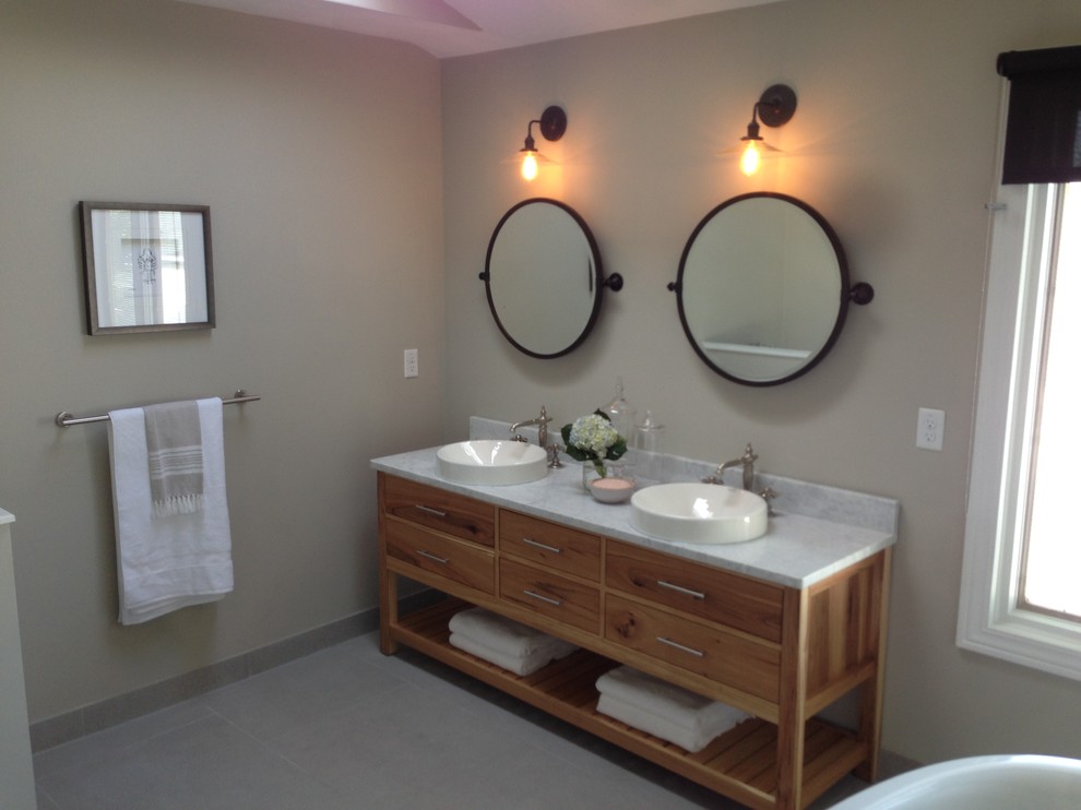 Photo of an expansive beach style master bathroom in Other with a vessel sink, furniture-like cabinets, medium wood cabinets, marble benchtops, a freestanding tub, a double shower, a two-piece toilet, white tile, subway tile, beige walls and slate floors.