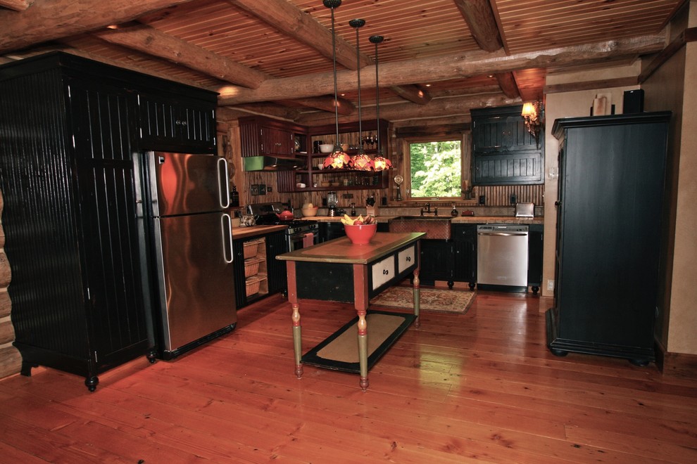 Inspiration for a mid-sized rustic l-shaped medium tone wood floor eat-in kitchen remodel with a farmhouse sink, shaker cabinets, black cabinets, brown backsplash, wood backsplash, stainless steel appliances and an island