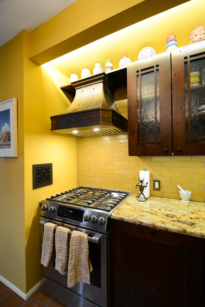 This is an example of a mid-sized single-wall open plan kitchen in New York with an undermount sink, recessed-panel cabinets, dark wood cabinets, quartzite benchtops, yellow splashback, subway tile splashback, stainless steel appliances, terra-cotta floors, with island, orange floor and multi-coloured benchtop.