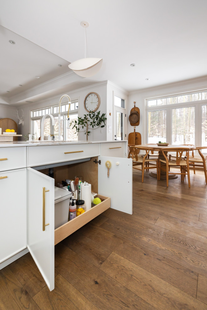 Example of a large beach style l-shaped light wood floor open concept kitchen design with shaker cabinets, white cabinets, quartz countertops, an island and white countertops