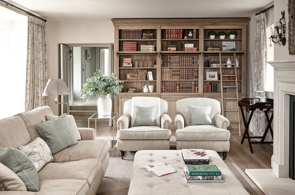 Photo of a traditional enclosed family room in Wiltshire with a library, beige walls, light hardwood floors and a standard fireplace.