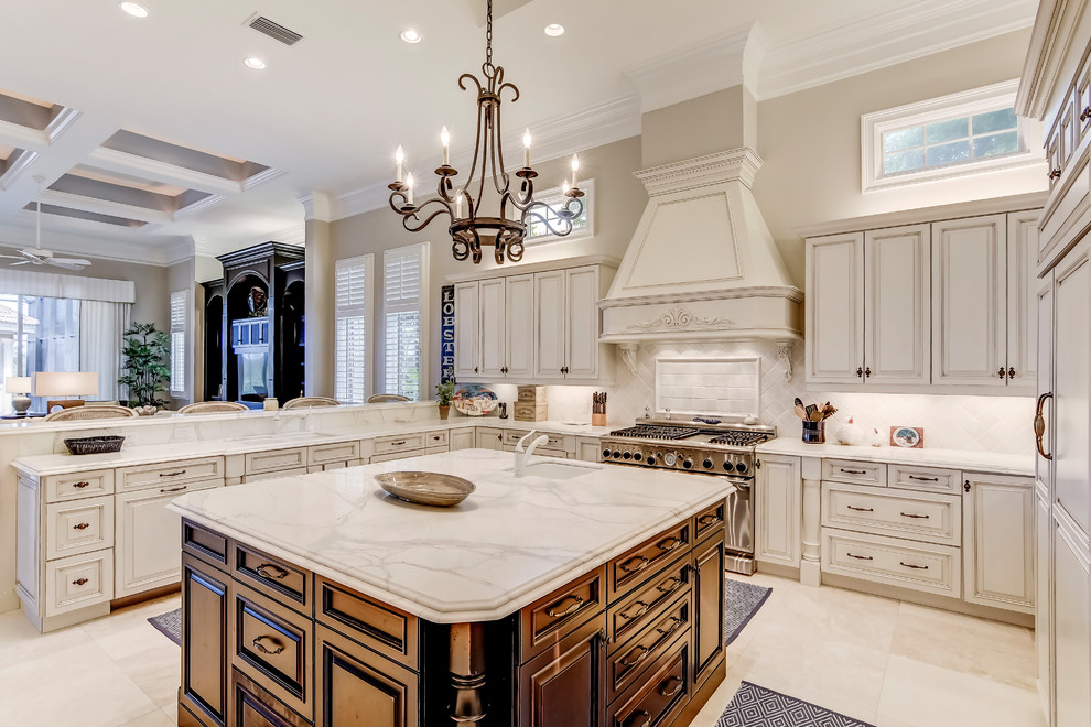 Photo of an expansive transitional u-shaped open plan kitchen in Miami with a double-bowl sink, raised-panel cabinets, distressed cabinets, marble benchtops, white splashback, porcelain splashback, panelled appliances, marble floors and with island.