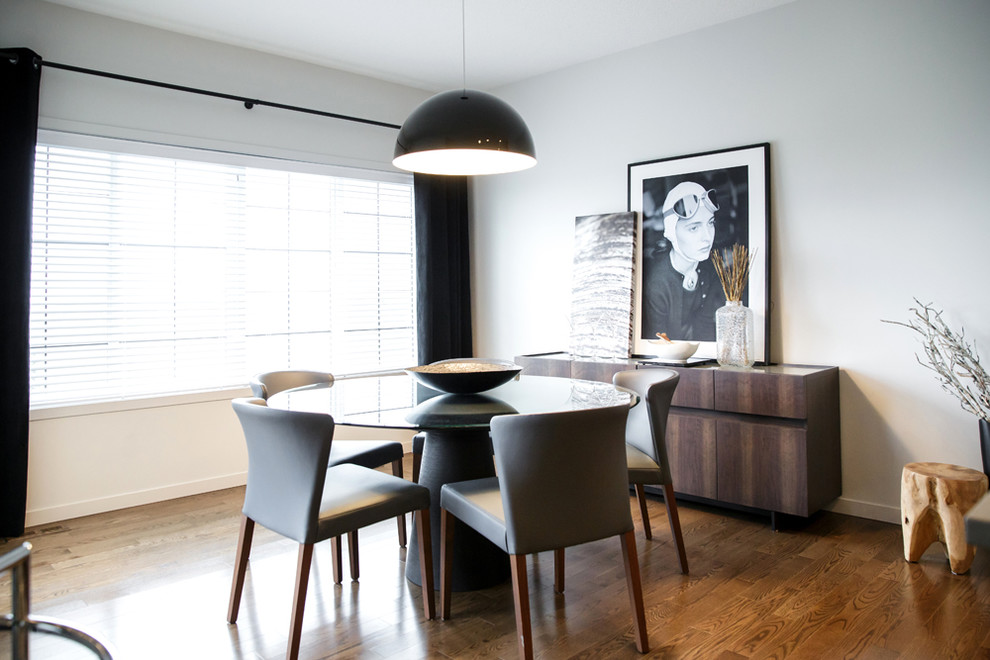 This is an example of a contemporary dining room in Calgary with white walls and dark hardwood floors.