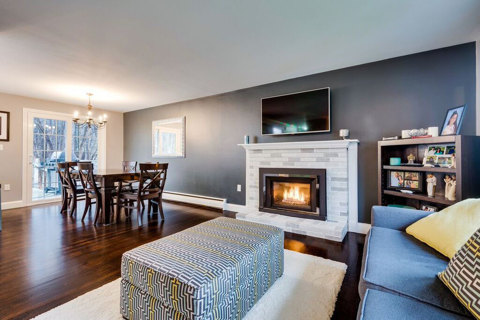 Inspiration for a mid-sized transitional open concept family room in Boston with grey walls, dark hardwood floors, a standard fireplace, a plaster fireplace surround, a wall-mounted tv and brown floor.