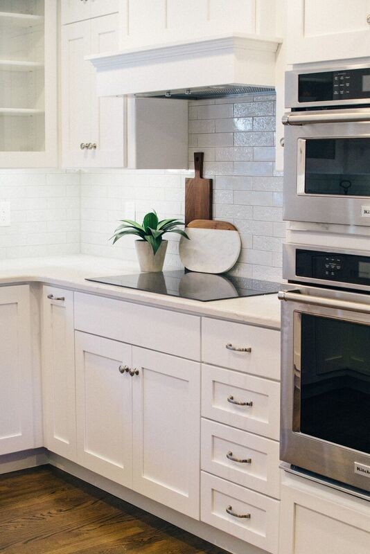 Inspiration for a mid-sized u-shaped dark wood floor and brown floor open concept kitchen remodel with a farmhouse sink, recessed-panel cabinets, white backsplash, glass tile backsplash, stainless steel appliances and an island