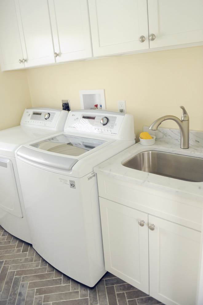 Small transitional galley utility room in Baltimore with an undermount sink, shaker cabinets, white cabinets, marble benchtops, yellow walls, ceramic floors, a side-by-side washer and dryer and grey floor.