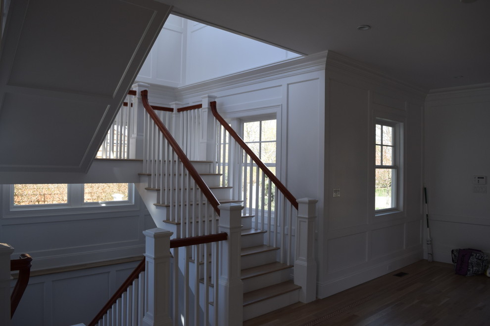 This is an example of a large traditional wood u-shaped staircase in New York with painted wood risers and wood railing.