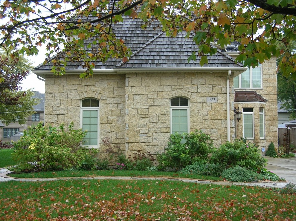 Inspiration for a mid-sized traditional two-storey yellow house exterior in Other with stone veneer and a shingle roof.