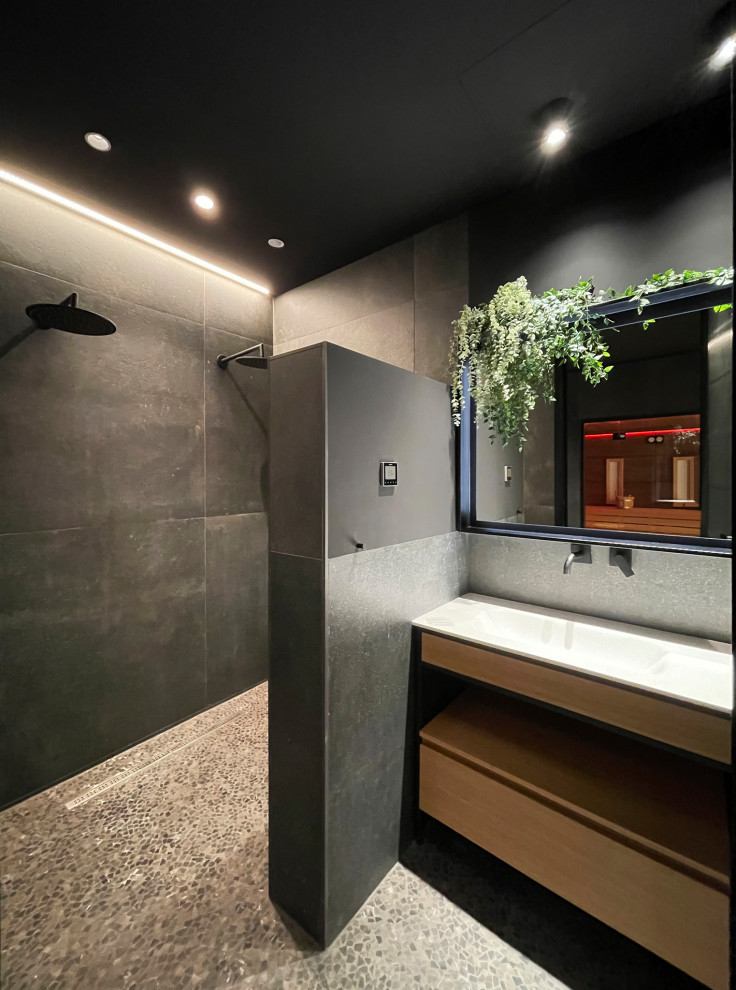 Design ideas for a large world-inspired grey and black sauna bathroom in Other with flat-panel cabinets, medium wood cabinets, a double shower, a wall mounted toilet, black tiles, ceramic tiles, white walls, marble flooring, a built-in sink, solid surface worktops, black floors, white worktops, a single sink and a built in vanity unit.