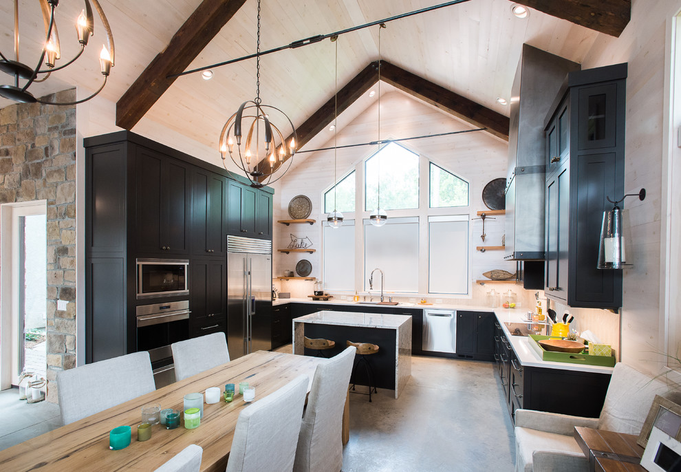 Large beach style u-shaped open plan kitchen in Minneapolis with an undermount sink, shaker cabinets, grey cabinets, quartz benchtops, beige splashback, stone tile splashback, stainless steel appliances, concrete floors and with island.