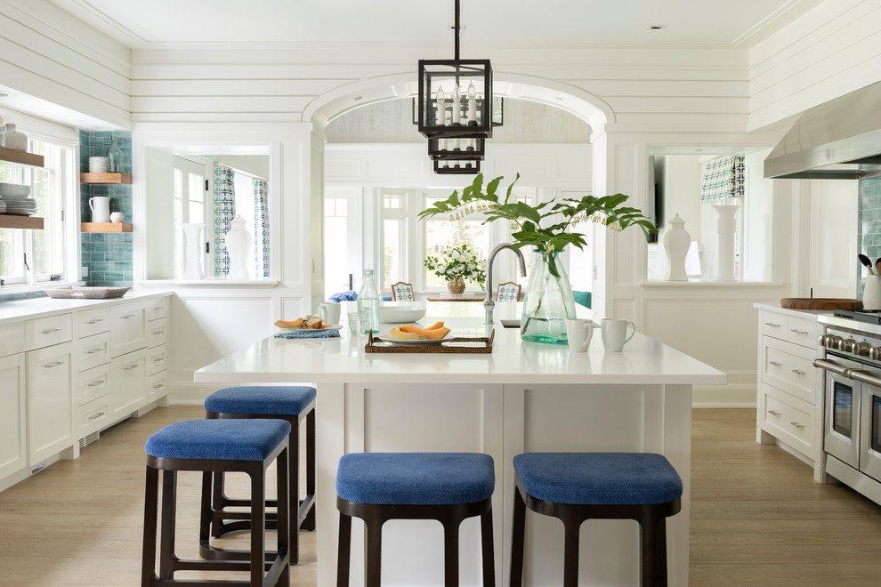 This is an example of a beach style separate kitchen in Boston with an undermount sink, shaker cabinets, white cabinets, green splashback, subway tile splashback, stainless steel appliances, light hardwood floors, with island, beige floor and white benchtop.