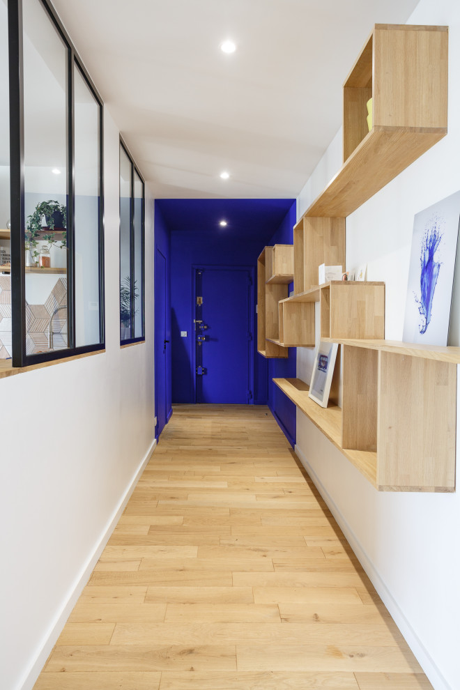Inspiration for a mid-sized modern entry hall in Paris with multi-coloured walls, light hardwood floors, a single front door, a blue front door and beige floor.