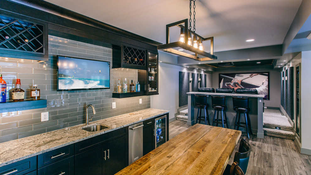This is an example of a modern single-wall wet bar in DC Metro with an undermount sink, shaker cabinets, black cabinets, granite benchtops, grey splashback, subway tile splashback, dark hardwood floors and brown floor.