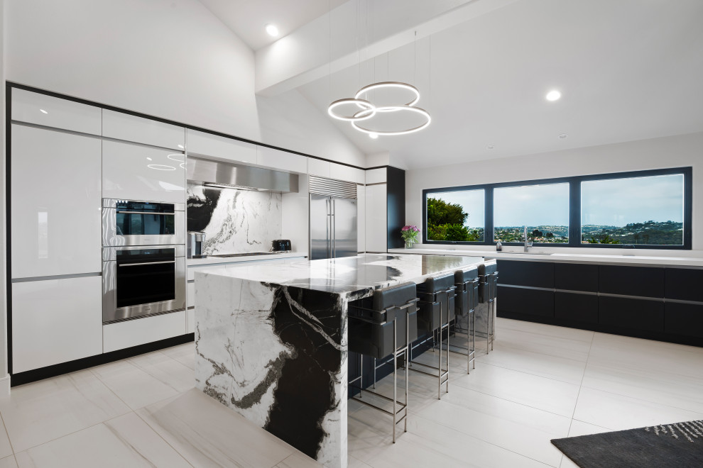 Inspiration for a mid-sized contemporary eat-in kitchen in Orange County with an undermount sink, flat-panel cabinets, black cabinets, marble benchtops, marble splashback, stainless steel appliances, porcelain floors, with island, white floor and exposed beam.