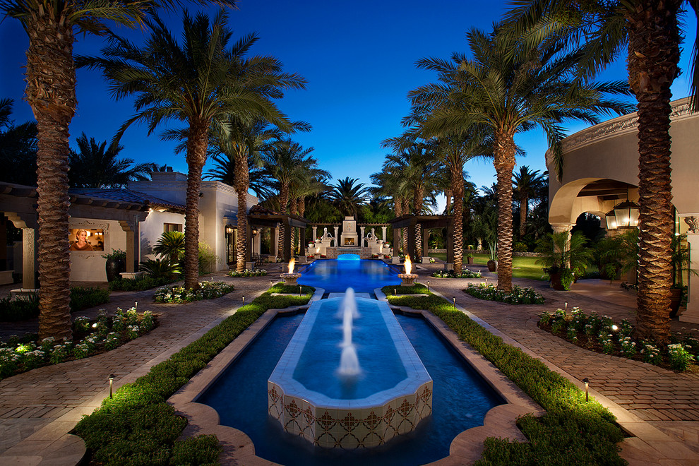 Photo of an expansive mediterranean backyard partial sun formal garden in Phoenix with a water feature and brick pavers.