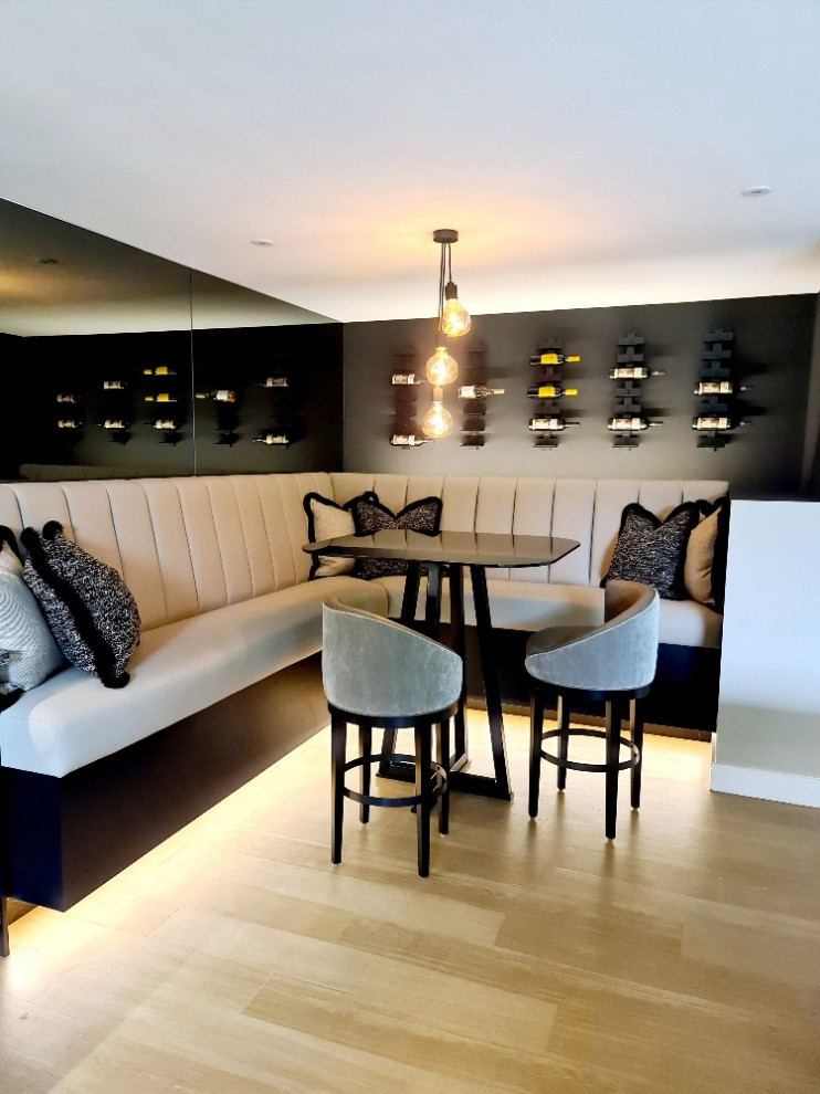 Large contemporary home bar in Other with flat-panel cabinets, granite worktops, black splashback, granite splashback, medium hardwood flooring, black worktops and feature lighting.