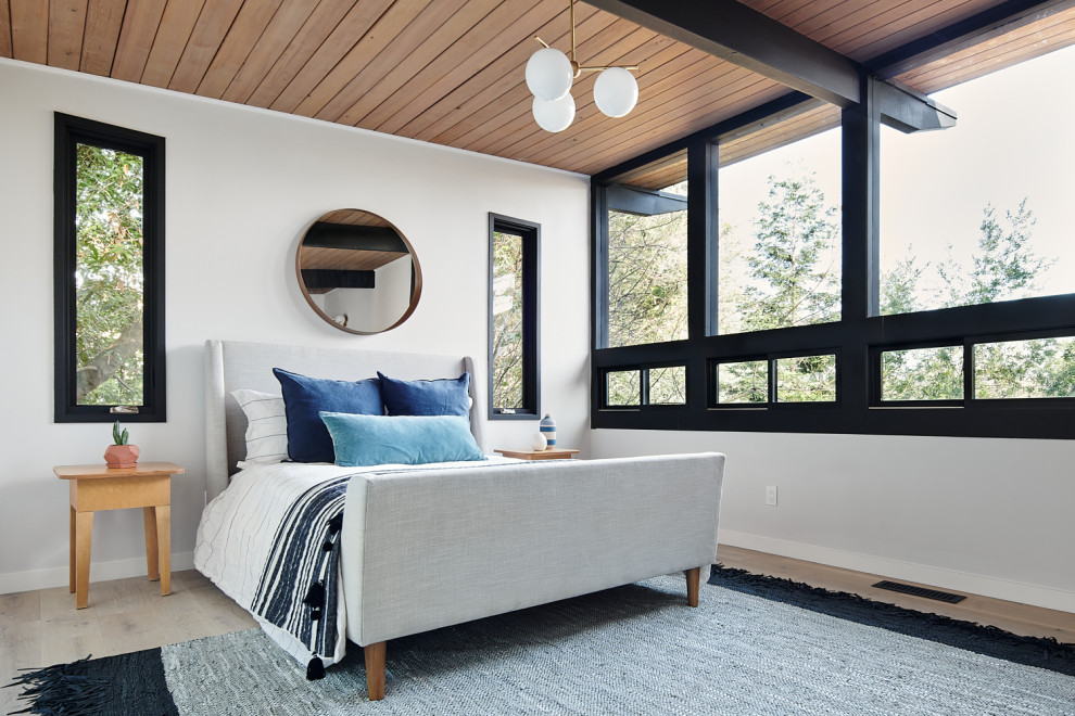 Photo of a midcentury bedroom in San Francisco with white walls, light hardwood floors, beige floor, exposed beam and wood.