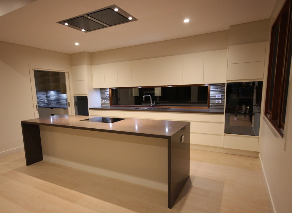Design ideas for a large modern single-wall kitchen in Sydney with an undermount sink, flat-panel cabinets, quartz benchtops, matchstick tile splashback, bamboo floors, with island and black appliances.