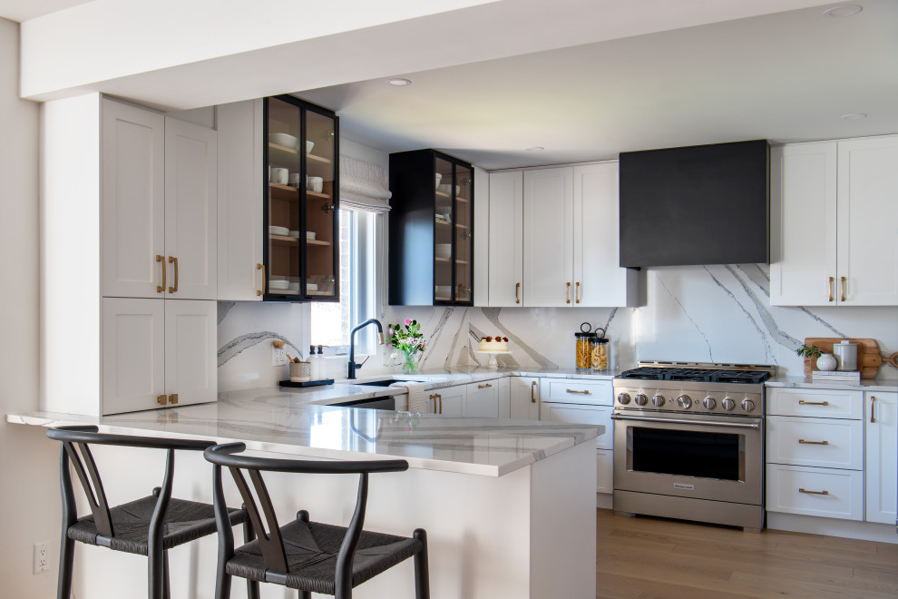 Eat-in kitchen - mid-sized transitional u-shaped medium tone wood floor eat-in kitchen idea with an undermount sink, shaker cabinets, white cabinets, quartz countertops, white backsplash, quartz backsplash, stainless steel appliances, a peninsula and white countertops
