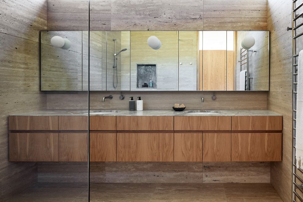 Large coastal bathroom in Melbourne with freestanding cabinets, medium wood cabinets, a walk-in shower, beige tiles, travertine tiles, beige walls, travertine flooring, a submerged sink, marble worktops, beige floors, an open shower, grey worktops, double sinks and a floating vanity unit.