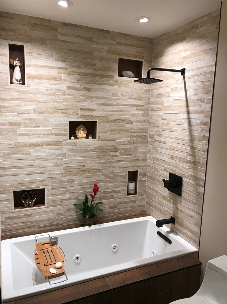 Photo of a small modern 3/4 bathroom in Seattle with brown cabinets, a drop-in tub, an alcove shower, a one-piece toilet, beige tile, porcelain tile, beige walls, porcelain floors, an undermount sink, marble benchtops, brown floor, a hinged shower door and white benchtops.