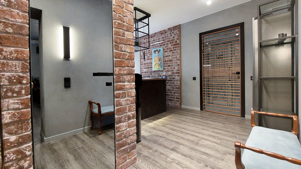 Идея дизайна: большая узкая прихожая: освещение в стиле лофт с серыми стенами, паркетным полом среднего тона, одностворчатой входной дверью, серой входной дверью, коричневым полом и кирпичными стенами