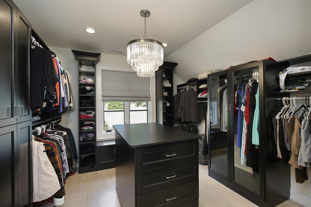 Transitional women's walk-in wardrobe in Chicago with open cabinets, black cabinets, light hardwood floors and beige floor.