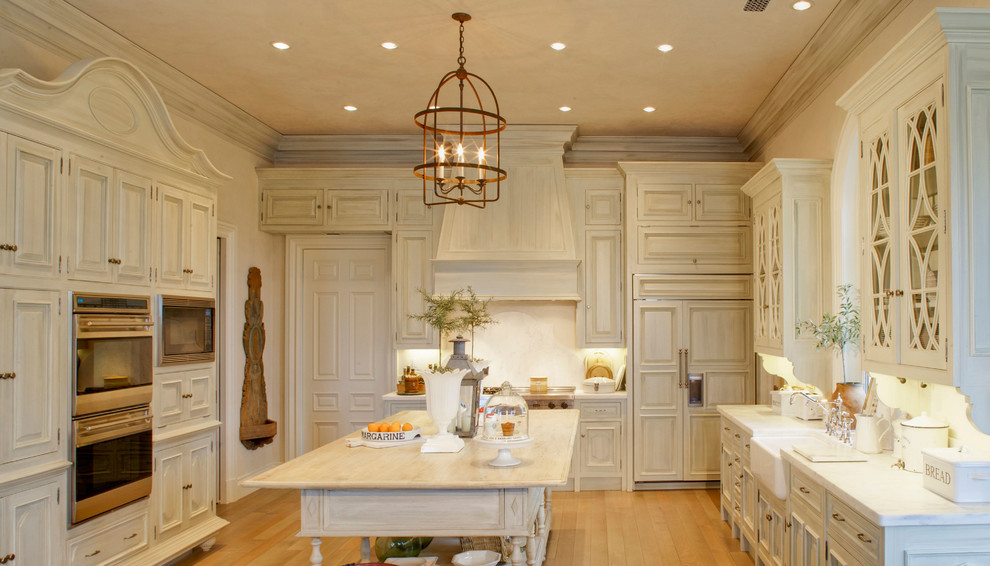 Design ideas for a large traditional u-shaped separate kitchen in Jacksonville with a farmhouse sink, recessed-panel cabinets, beige cabinets, marble benchtops, beige splashback, panelled appliances, medium hardwood floors, with island and brown floor.
