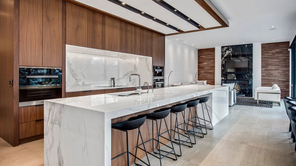 Contemporary galley open plan kitchen in Toronto with an undermount sink, flat-panel cabinets, medium wood cabinets, marble benchtops, multi-coloured splashback, black appliances, light hardwood floors, with island, beige floor, multi-coloured benchtop, recessed and wood.