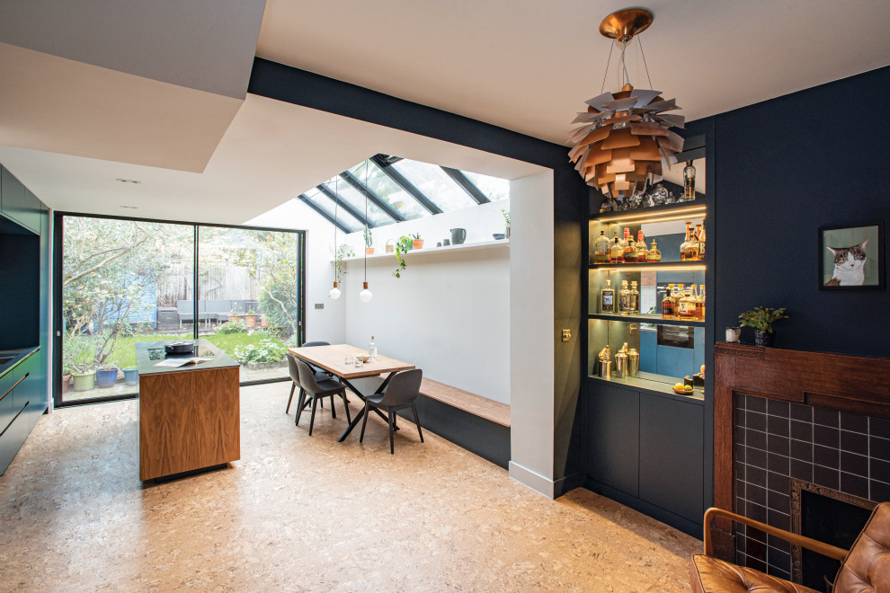 Design ideas for a mid-sized contemporary kitchen/dining combo in London with blue walls, cork floors, a corner fireplace, a wood fireplace surround and brown floor.