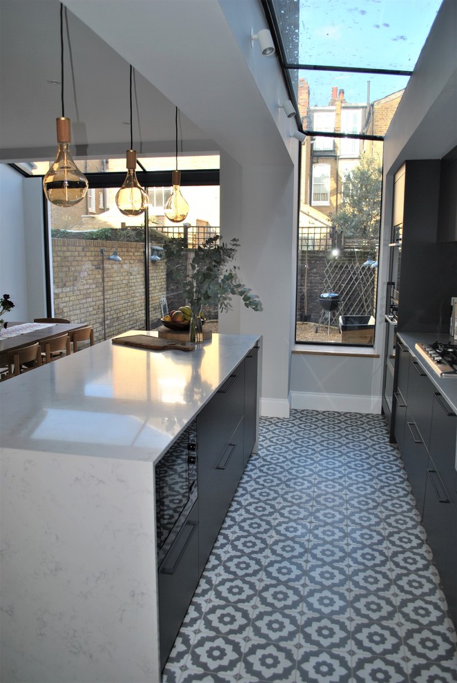 Photo of a contemporary eat-in kitchen in London with a farmhouse sink, flat-panel cabinets, grey cabinets, quartzite benchtops, white splashback, subway tile splashback, ceramic floors and multi-coloured floor.