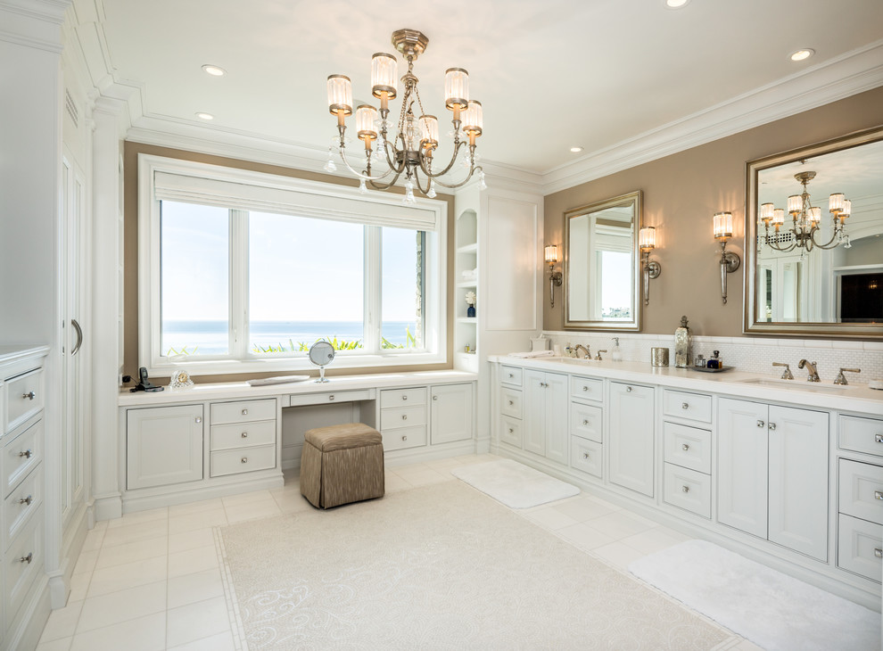 This is an example of a beach style bathroom in Orange County with an undermount sink, white cabinets, white tile and recessed-panel cabinets.