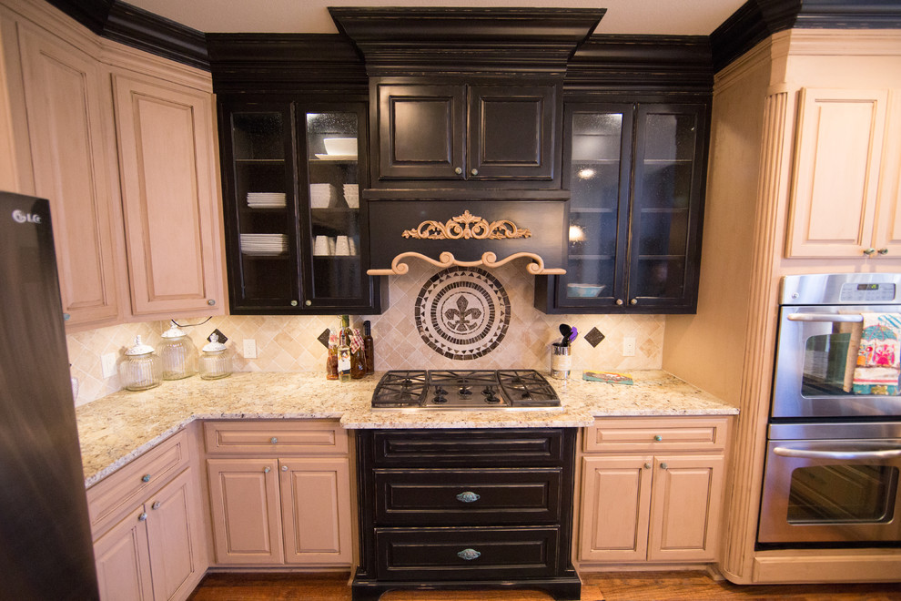This is an example of a mid-sized traditional separate kitchen in Dallas with a farmhouse sink, distressed cabinets, granite benchtops, beige splashback, stone tile splashback, stainless steel appliances and medium hardwood floors.