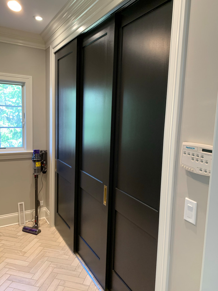 Photo of a small traditional gender neutral walk-in wardrobe in Chicago with shaker cabinets, black cabinets, porcelain flooring, beige floors and a coffered ceiling.