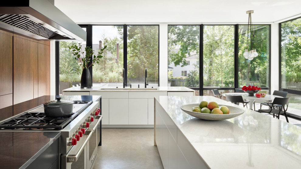 North Shore Less is More - Contemporary kitchen design, surrounded by full height window walls.  This minimal black & white kitchen features three islands with Chanel white and Double black quartzite countertops and concrete floors.  Walnut wall houses built-in refrigeration a and storage areas.  These touch-to-open full height walnut panels also conceal the pantry area and access to powder room and lower level.
