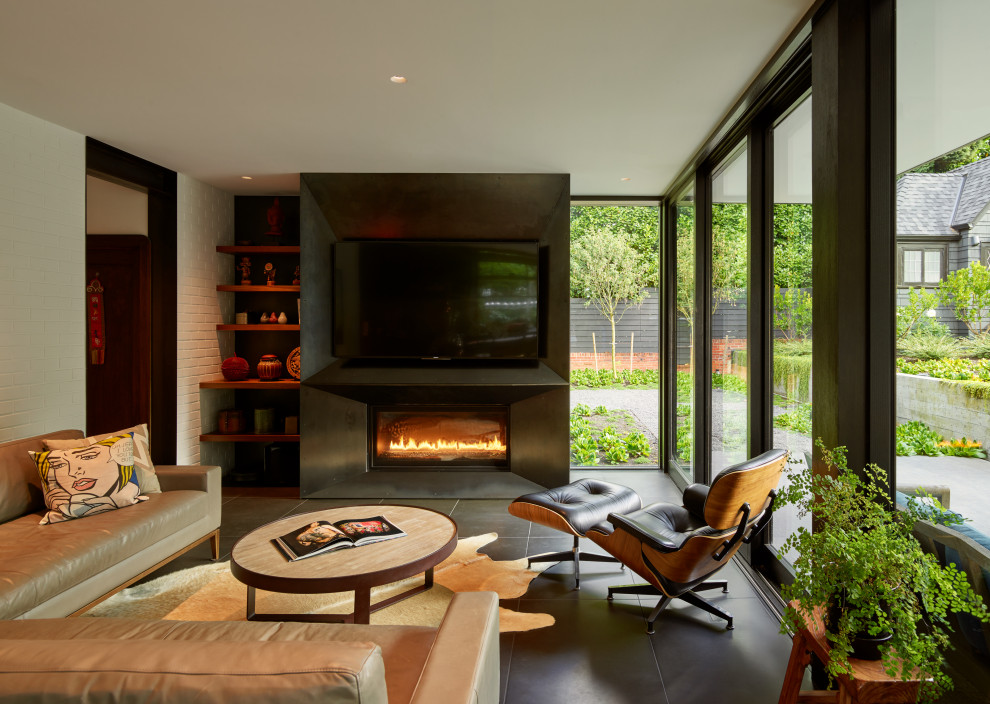 Design ideas for a large eclectic enclosed family room in Seattle with white walls, a ribbon fireplace, a metal fireplace surround, a wall-mounted tv, black floor and brick walls.