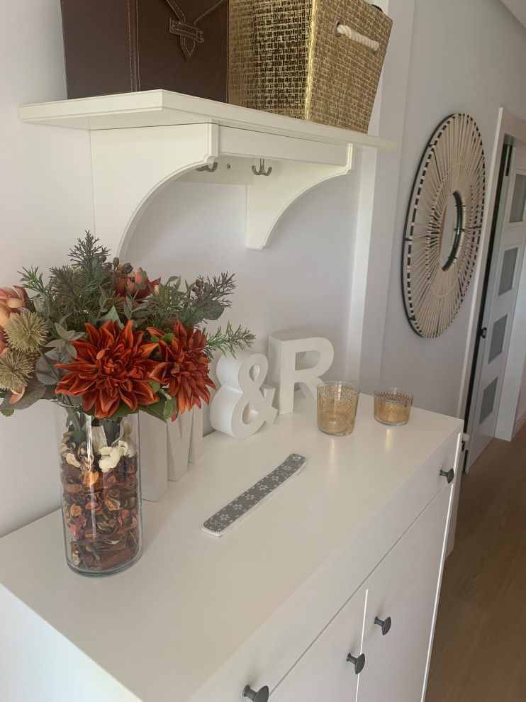 Imagen de entrada clásica renovada de tamaño medio con paredes blancas, suelo de madera clara, puerta simple y puerta blanca