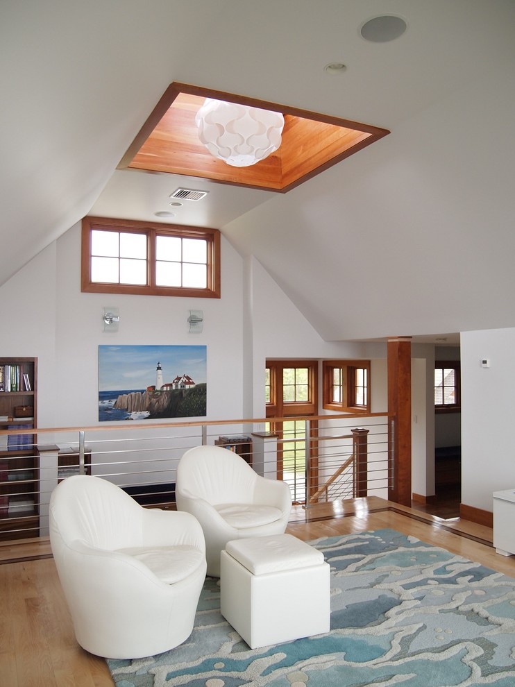 This is an example of a beach style loft-style family room in Portland Maine with white walls and light hardwood floors.